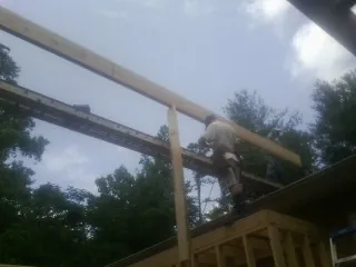 Carpenter setting a ridge beam over a new addition frame — Ice Dam Removal by Roofing Brothers in Middle Island