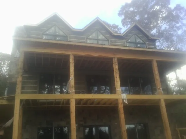 Dormers and porch framing on a large log home under construction — Roof Coating work by our crew in Middle Island
