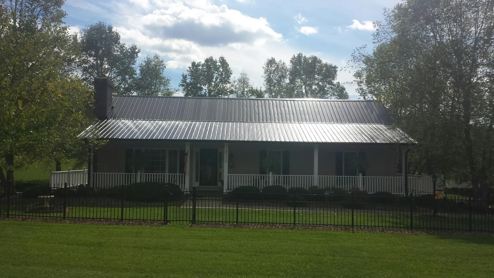 Gray metal roof on a brick ranch with a full width front porch — Gutter Guard Installation work by our crew in Middle Island