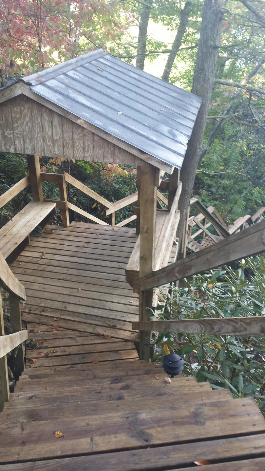 Metal roofed shelter over wooden steps on a wooded walkway — Skylight Repair & Installation work by our crew in Middle Island