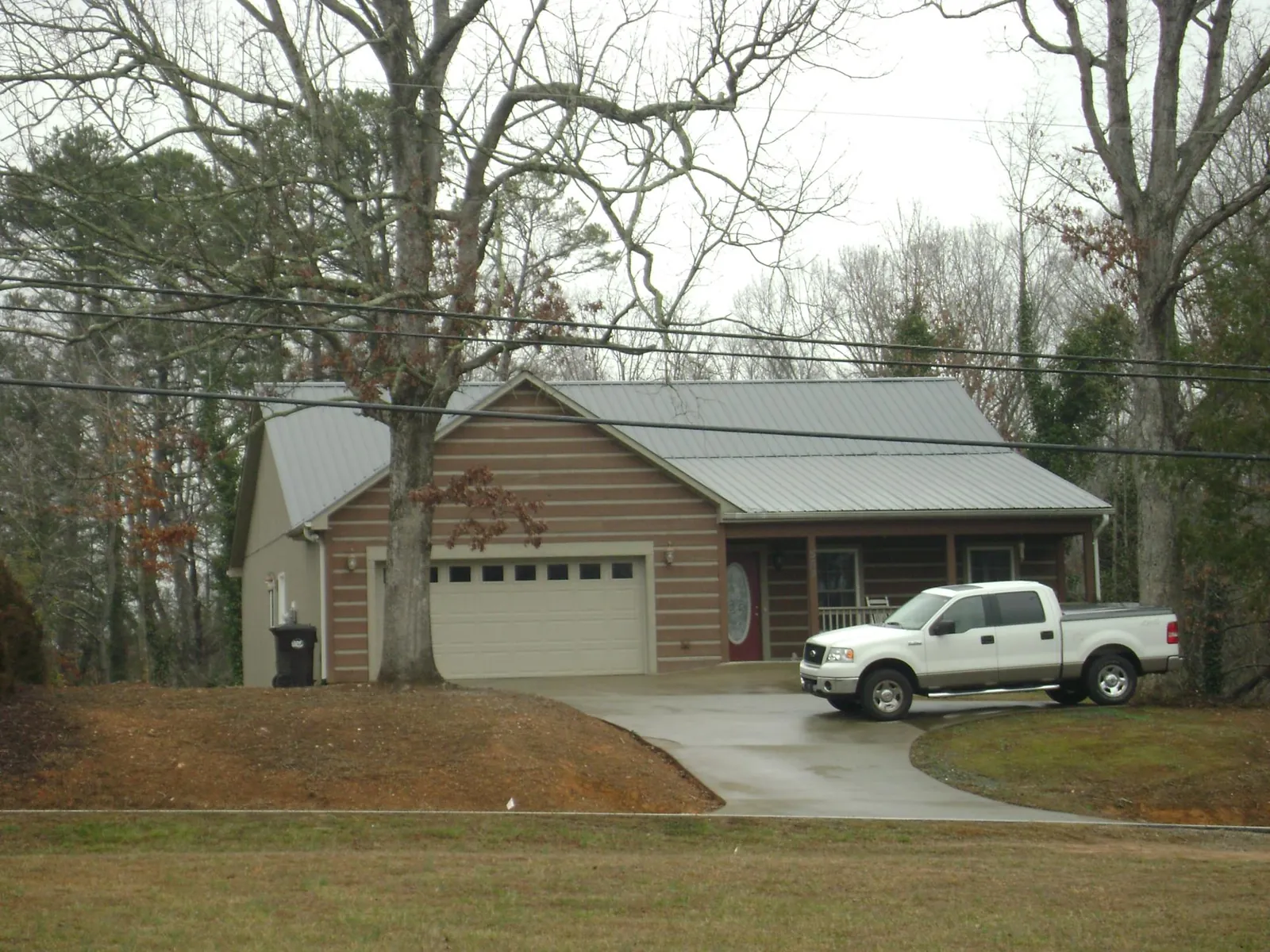 Gray metal roof on a log sided house with an attached two car garage in Middle Island