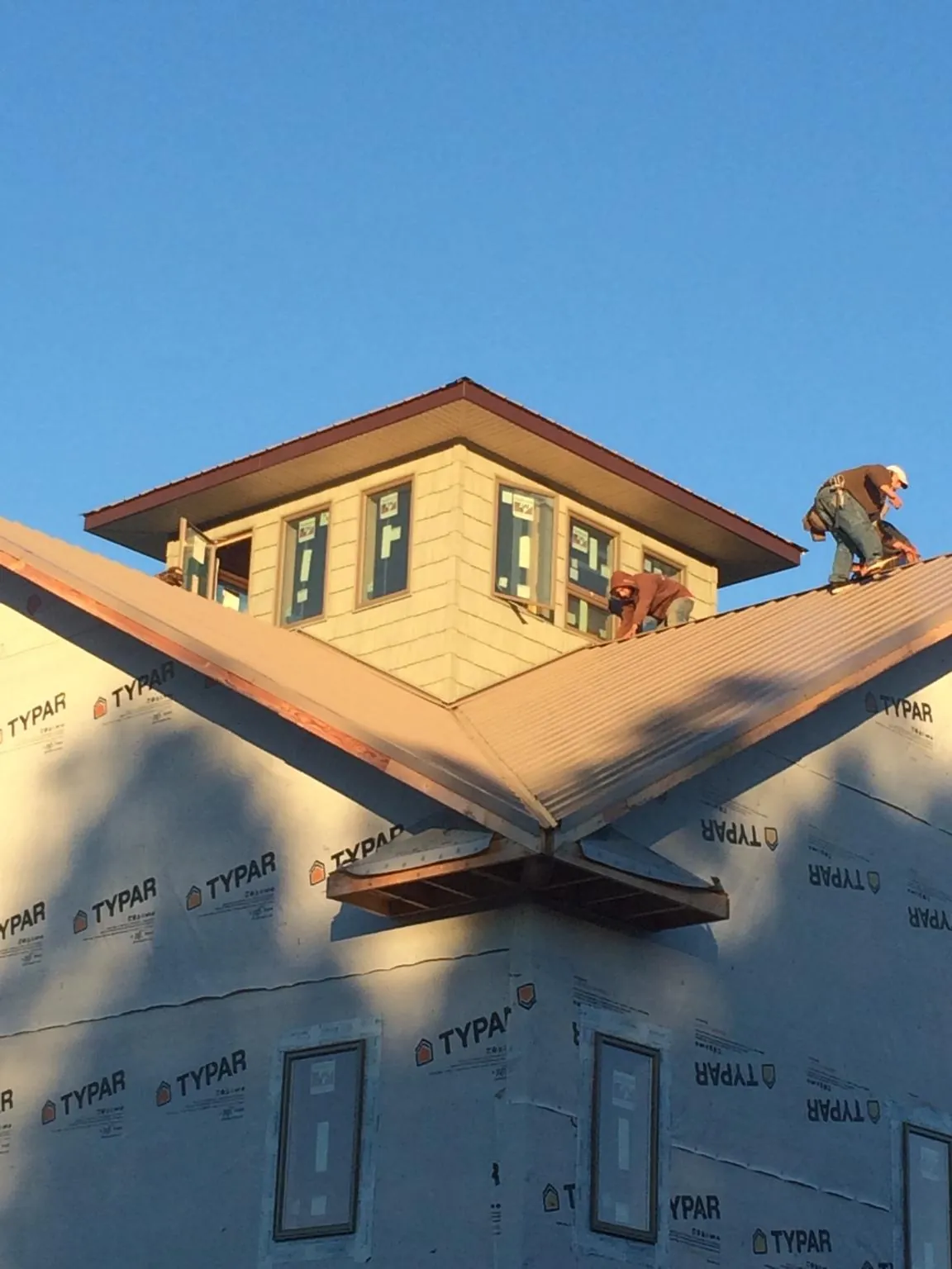 Roofers working around a rooftop cupola on a new metal roof at sunset — Roof Waterproofing in Middle Island by Roofing Brothers